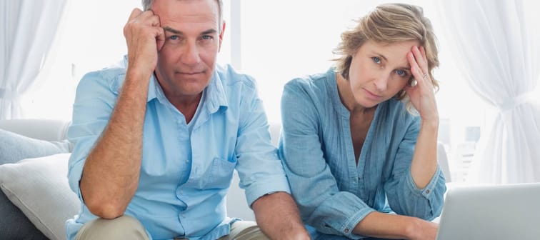 Anxious couple paying their bills online with laptop at home in the living room