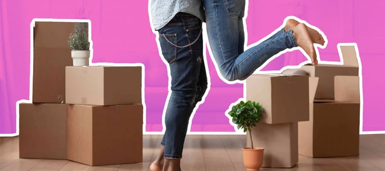 close up from the waist down of a young couple in a room, surrounded by boxes, woman is being lifted up with her knees bent, legs in the air