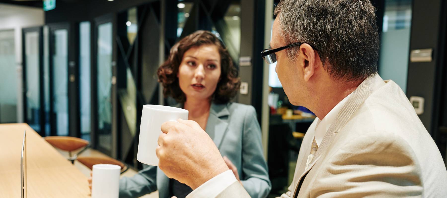 middle-aged business people drinking coffee and discussing sales and company development