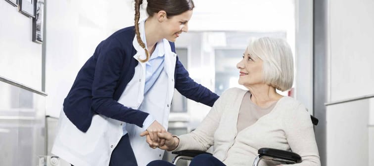 Physiotherapist Consoling Senior Woman Sitting In Wheelchair