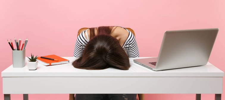 Young frustrated exhausted woman laid her head down on the table sit work at white desk with contemporary pc laptop