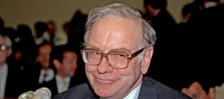 Photo of Warren Buffet in front of a microphone grinning