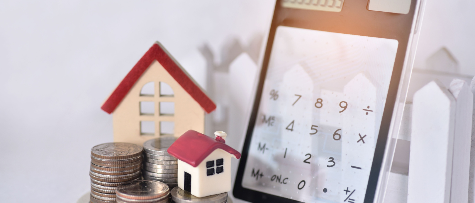 Stacking coins with the two red roof house and the calculator lean against the sunrise for calculate the home payment interest of house loan