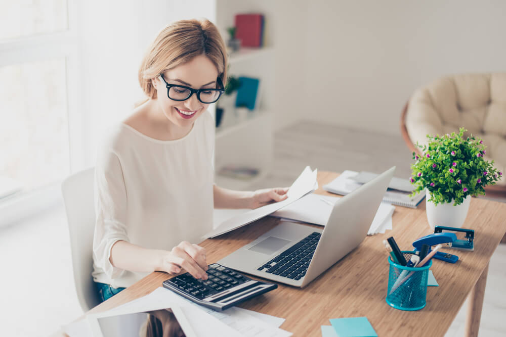 Woman working with computer and calculator at desk