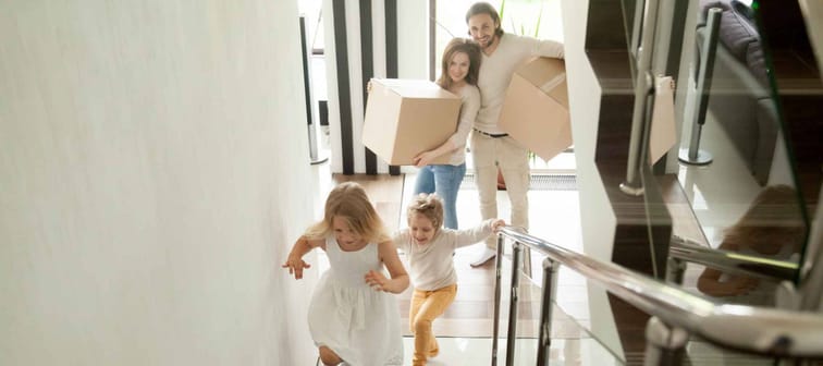 Happy children going upstairs inside two story big house,