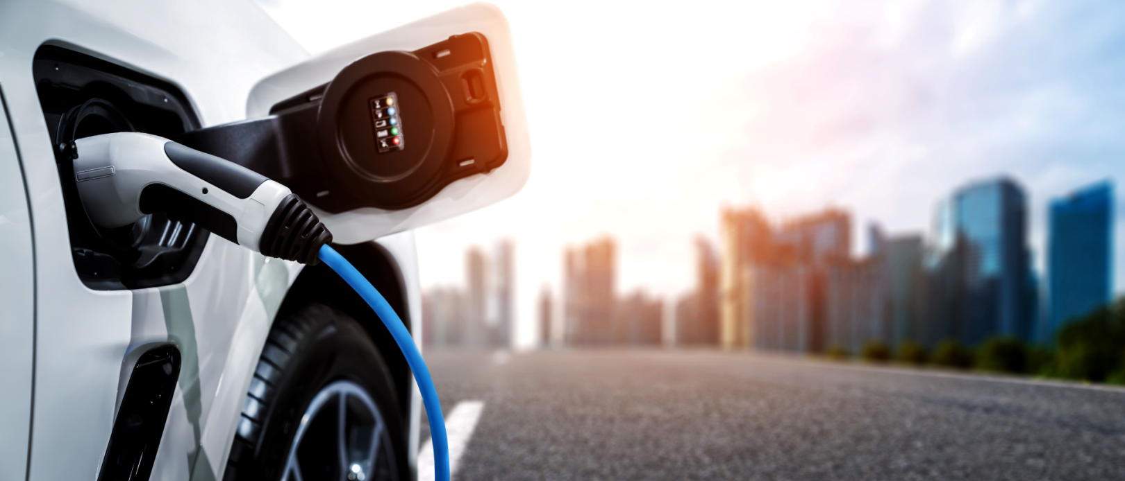 Businessman holding smartphone while charging car at electric vehicle charging station, closeup.